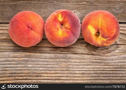 three fresh yellow peach fruits on weathered grained wood with a copy space