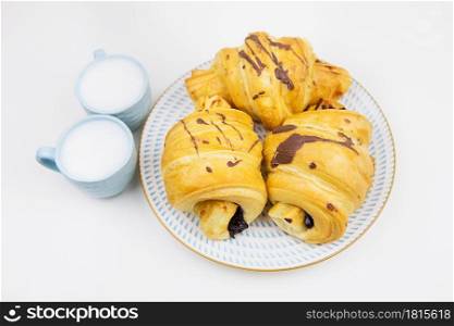 three freshly baked croissants on a white ceramic plate, two cups of coffee.. three freshly baked croissants on a white ceramic plate, two cups of coffee