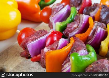 Three freshly prepared beef shish-ka-bob with vegetables, marinated and ready for the grill. Shallow depth of field.