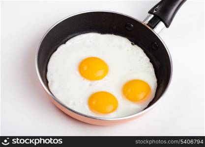 three fried egg on teflon pan without oil isolated on white