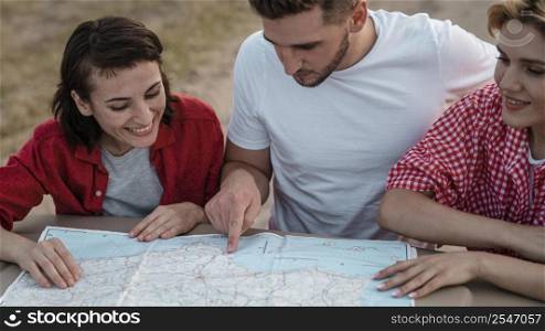three friends checking map together while traveling by car