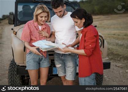 three friends checking map while traveling by car