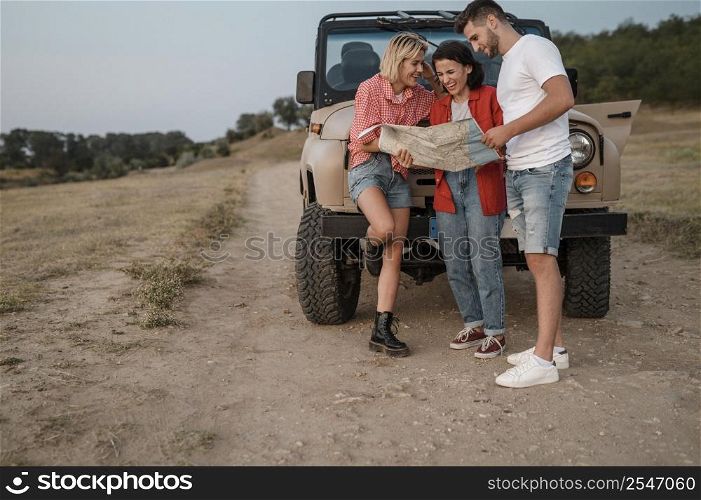 three friends checking map while traveling by car together