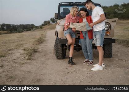 three friends checking map while traveling by car together