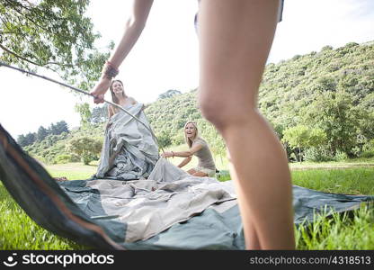 Three friends constructing tent whilst camping
