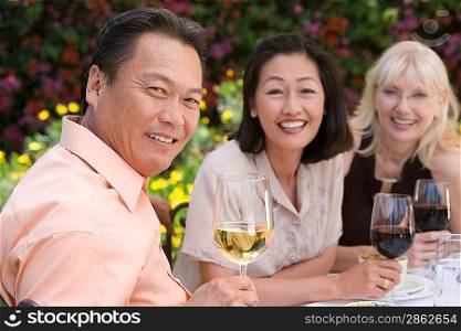 Three friends drinking wine outdoors, portrait
