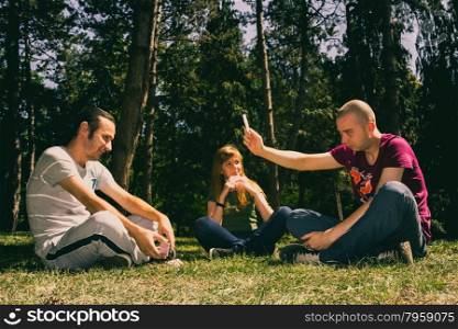 Three friends having fun by playing cards in the forest