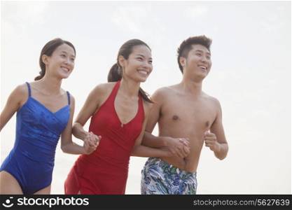 Three friends holding hands and smiling on the beach