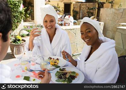 Three friends in bathrobes, eating outdoors