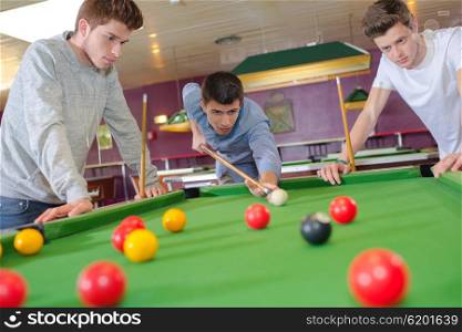 Three friends playing pool
