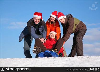 three friends push girl on sled