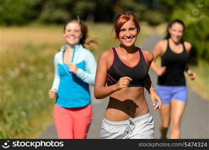 Three friends running outdoors on sunny day smiling