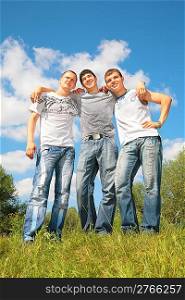 Three friends stand on grass
