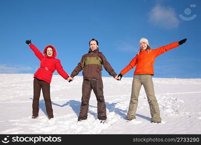 three friends stand on snow on hillside