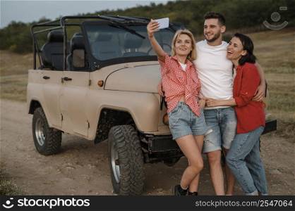 three friends taking selfie while traveling by car