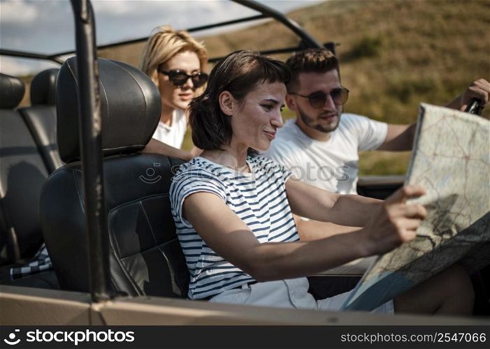 three friends traveling by car checking map 3