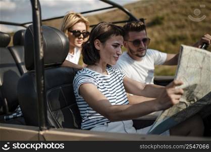 three friends traveling by car checking map 3