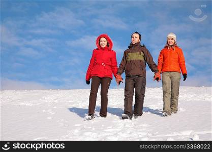 three friends walk on snow on hillside 2