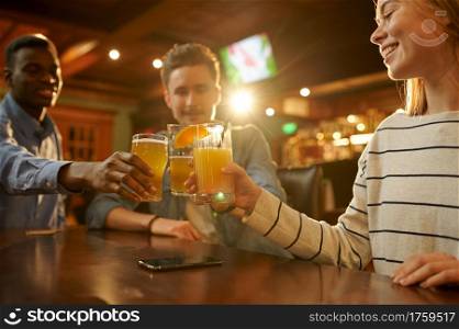 Three friends with alcohol beverages having fun at the table in bar. Group of people relax in pub, night lifestyle, friendship, event celebration. Friends with alcohol beverages having fun in bar