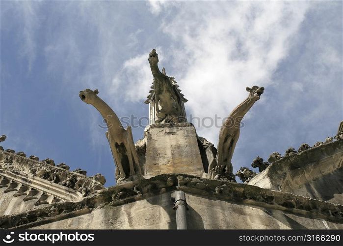 Three gargoyles on church roof against blue sky
