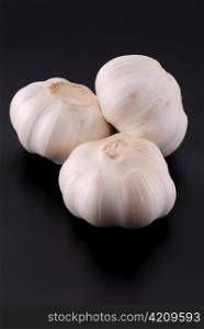 Three garlics on black background