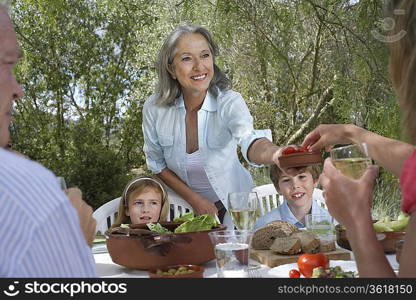 Three-generation family including two children (5-6) eating at garden table