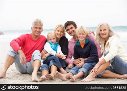 Three Generation Family Sitting On Winter Beach Together