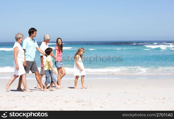 Three Generation Family Walking Along Sandy Beach