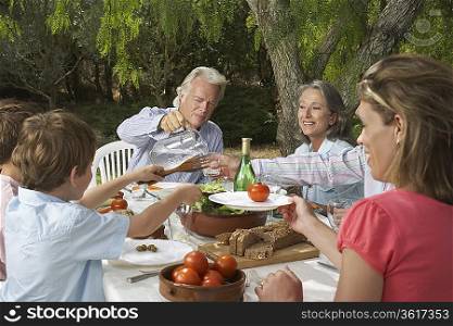 Three-generation family with children (6-11) dining in garden