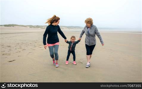 Three generations female running on the beach in autumn. Three generations female running on the beach