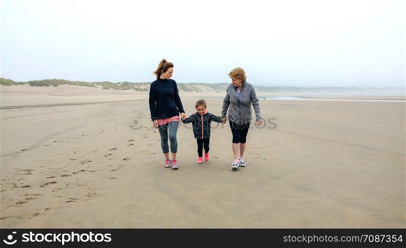 Three generations female walking on the beach in autumn. Three generations female walking on the beach