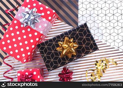 Three gift boxes red in white polka dots and black with gold, red and gold serpentine, red bow on wrapping black and gold and white and gold paper.
