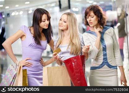 Three girlfriends in shop with bags and a credit card