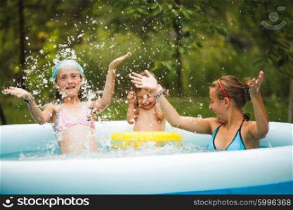 Three girls are swimming in the blue pool and playing. Girls in swimming pool