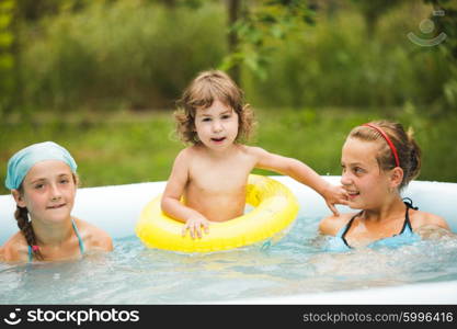 Three girls are swimming in the blue pool and playing with ball. Girls in swimming pool