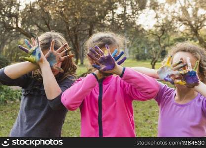 three girls covering their faces with painted palms. High resolution photo. three girls covering their faces with painted palms. High quality photo