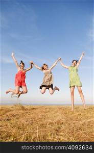 Three girls jump and hold hands up high