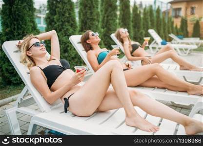 Three girls relax and sunbathig on deck chairs, summertime. Young sexy women on summer vacations. Three girls relax and sunbathig on deck chairs