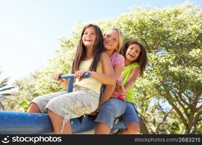 Three Girls Riding On See Saw In Playground