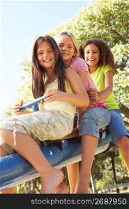 Three Girls Riding On See Saw In Playground