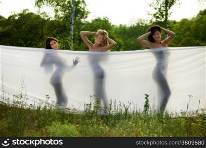 three girls wrapped in white fabric. outdoor shot