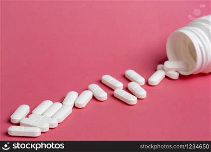 three glass bottles of pills on a pink background of scattered white drugs. Plastic white bottles of pills on a pink background of scattered white pills