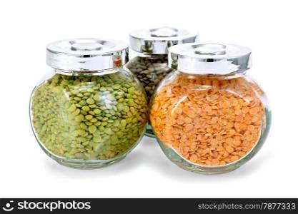 Three glass jars with green, red, brown lentils isolated on white background