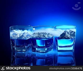 Three glasses of blue liquid with mountain illustration in