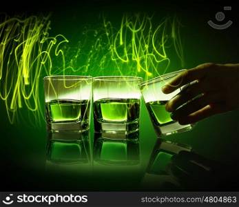 Three glasses of green absinth. Hand holding one of three glasses of green absinth with fume going out