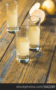 Three glasses of limoncello on the wooden background