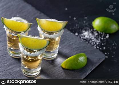 Three glasses of mexican tequila and lime on a dark background. Three glasses of mexican tequila and lime on dark background