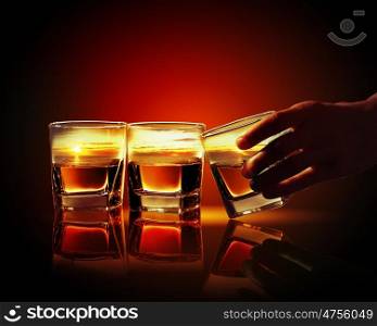 Three glasses of whiskey. Hand holding one of three glasses of whiskey with sea illustration in