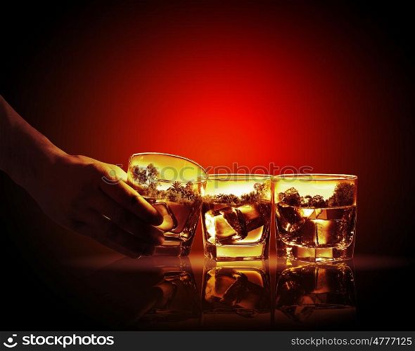 Three glasses of whiskey. Hand holding one of three glasses of whiskey with nature illustration in