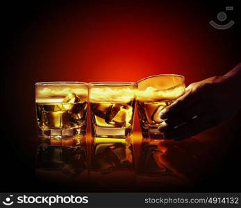 Three glasses of whiskey. Hand holding one of three glasses of whiskey with ice and sky illustration in